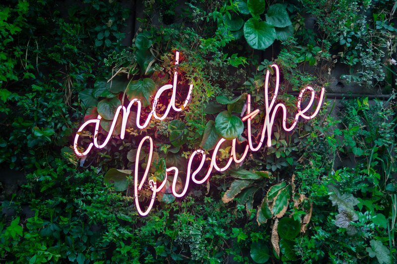 Neon sign saying Just Breath which indicates relaxation from a scalp massage